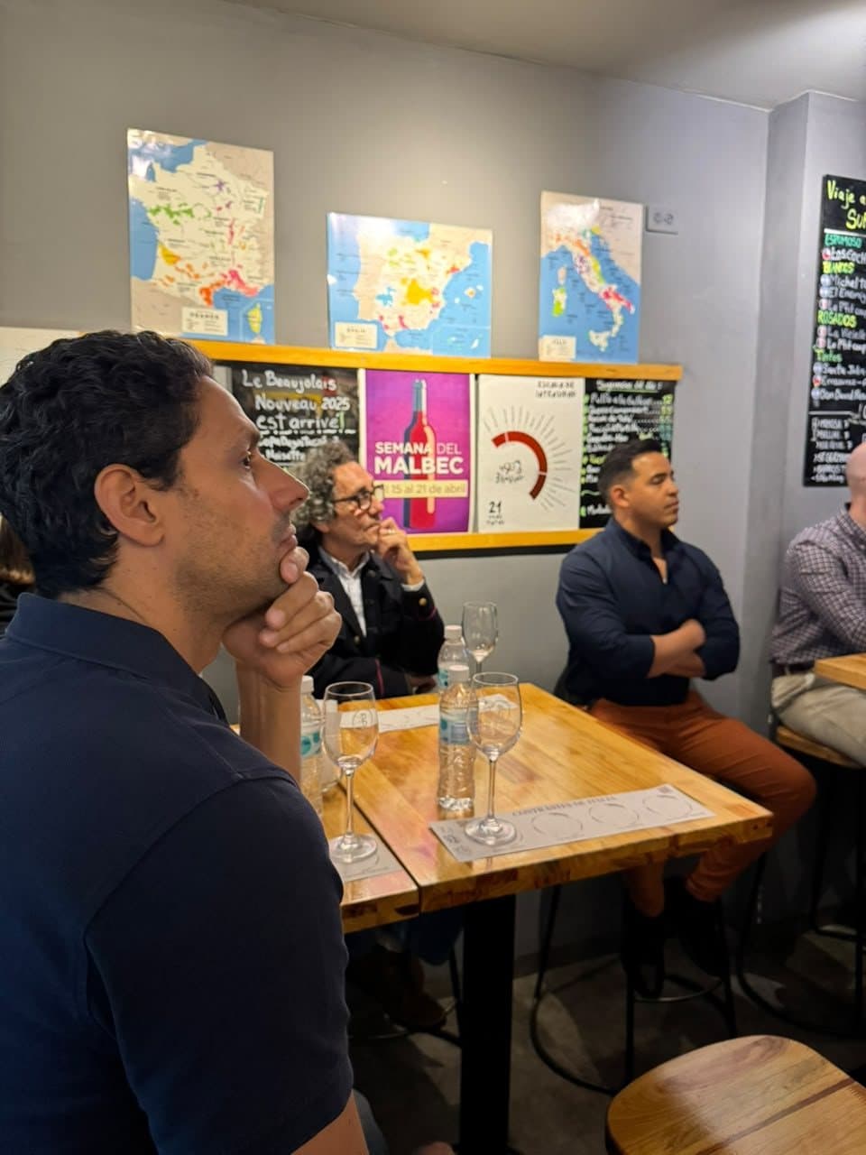 Invitado escuchando con atención frente a los mapas de regiones vinícolas